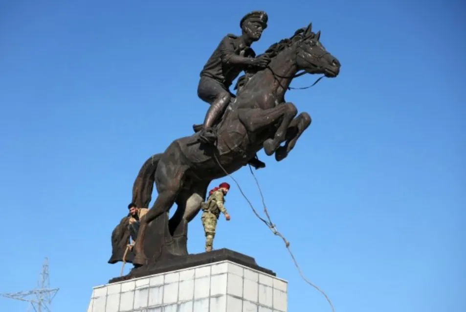 أشخاص يحطمون تمثالين لحافظ وباسل الأسد وتمزيق صورة للرئيس السوري بحلب